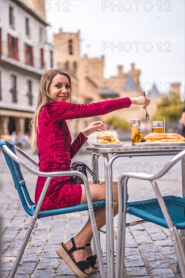 Portrait of a blonde woman having breakfast next to a medieval castle in summer