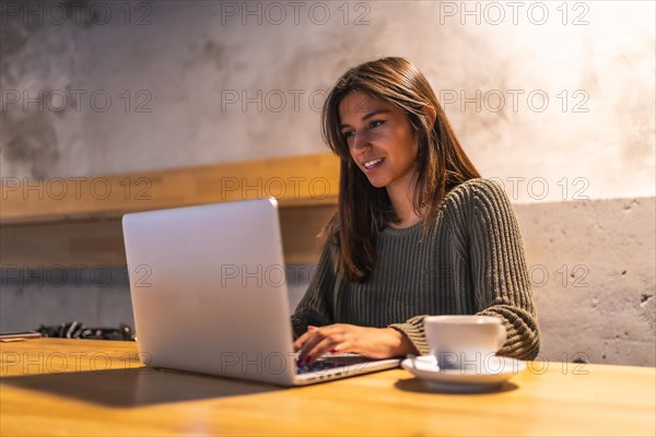 A young Caucasian brunette entrepreneur working from a coffee shop. Having a coffee