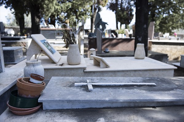 Grave with a single wilted flower in a vase and empty flower pots