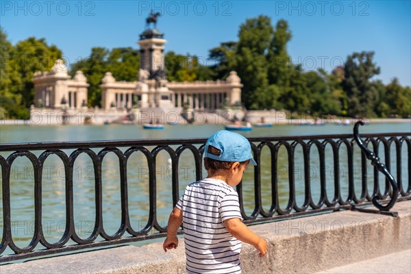 A boy walking next to the lake of the Estanque Grande de El Retiro in the city of Madrid. Spain