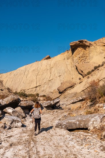 A young hiker with backpack and straw hat in the desert of Tabernas