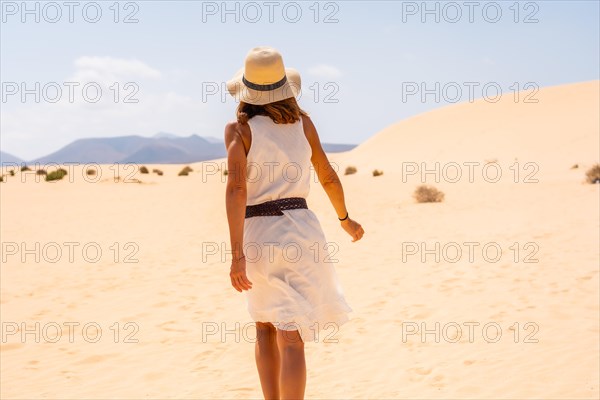 A young European tourist wearing a hat walking through the dunes of the Corralejo Natural Park