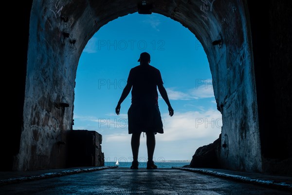 A young man in the tunnel to the sea at the Fort des Capucins a rocky islet located in the Atlantic Ocean