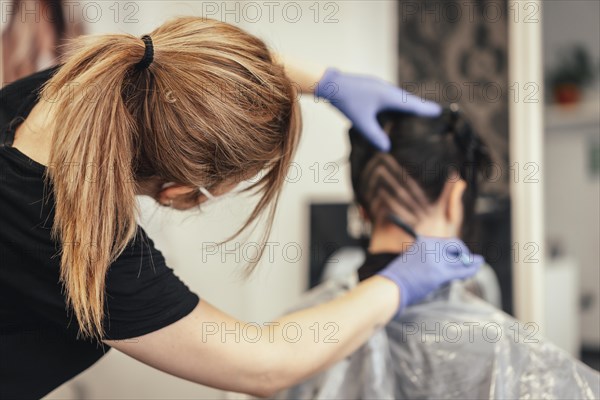 Hairdresser with mask shaving and making triangular drawings to the client. Reopening with security measures of Hairdressers in the Covid-19 pandemic