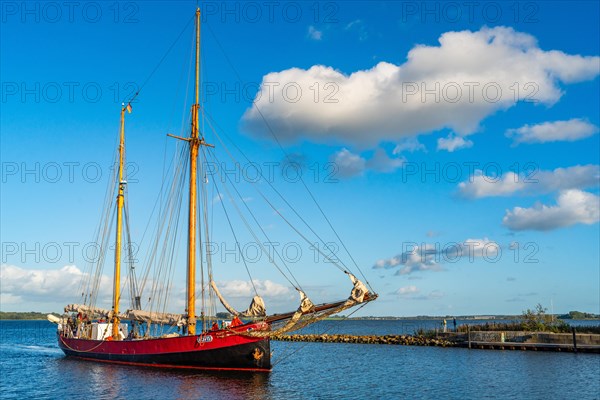 Red traditional sailing boat sails from the Greifswalder Bodden into the river Ryck