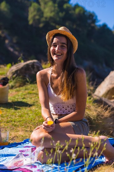 A young Caucasian couple at the picnic eating chips in the mountains by the sea enjoying the heat