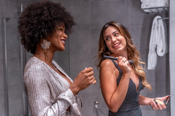 A young black girl with afro hair and a blonde Caucasian girl putting on makeup before the party with a smile. Exclusive party