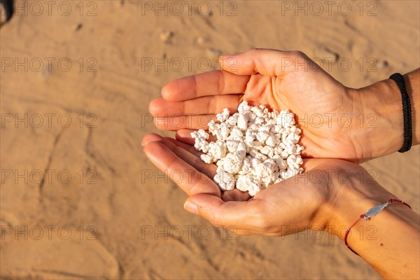 A young woman with stones in her hand on Popcorn Beach near the town of Corralejo