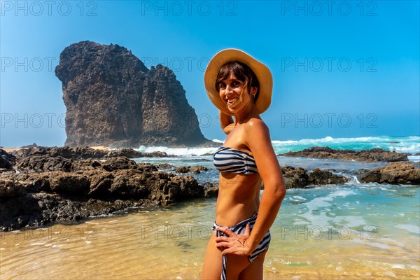 A young tourist smiling in the Roque del Moro of the Cofete beach of the natural park of Jandia