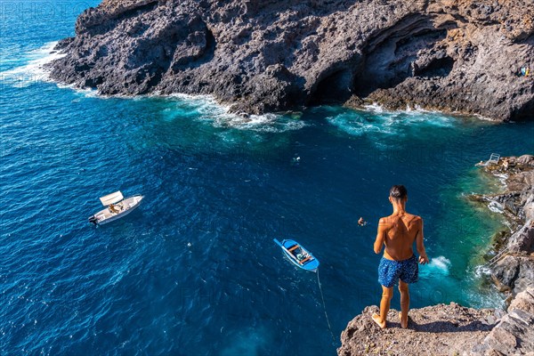 A young man making a very high jump into the water in the town of Poris de Candelaria on the north-west coast of the island of La Palma