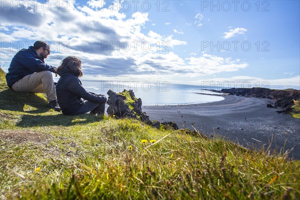 A couple in the beautiful black stone beach from above the Snaefellsnes coast. Iceland