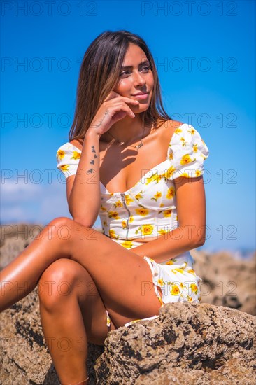 Portrait of a young woman in a white dress on the beach enjoying the summer