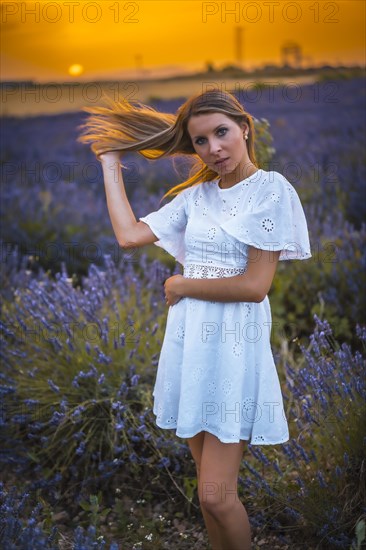 A young blonde Caucasian woman in a white dress in a cultivated lavender field in Navarra