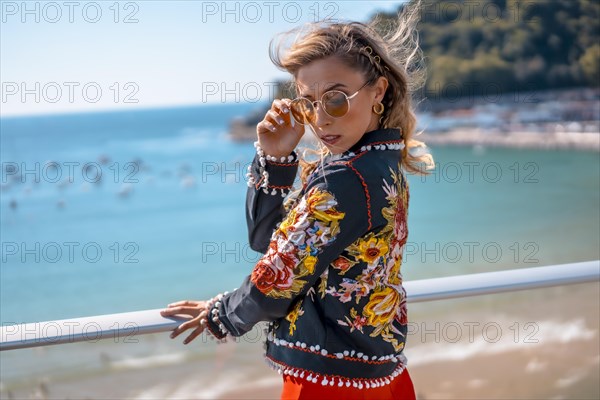 Portrait of a blonde woman on a terrace enjoying summer vacations with the sea in the background