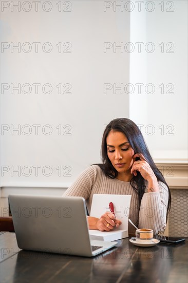 Brunette girl teleworking in a cafeteria with laptop