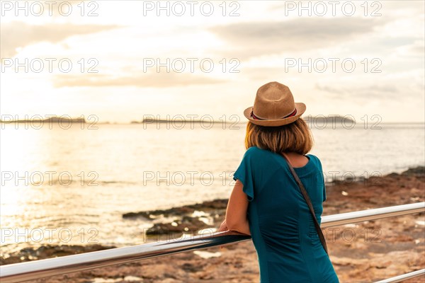 A young woman looking at the sunset on the Paseo de Poniente in San Antonio Abad