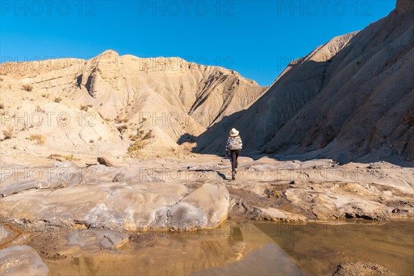 A young woman walking along the water in the desert on a trek in the Travertino waterfall and Rambla de Otero in the desert of Tabernas