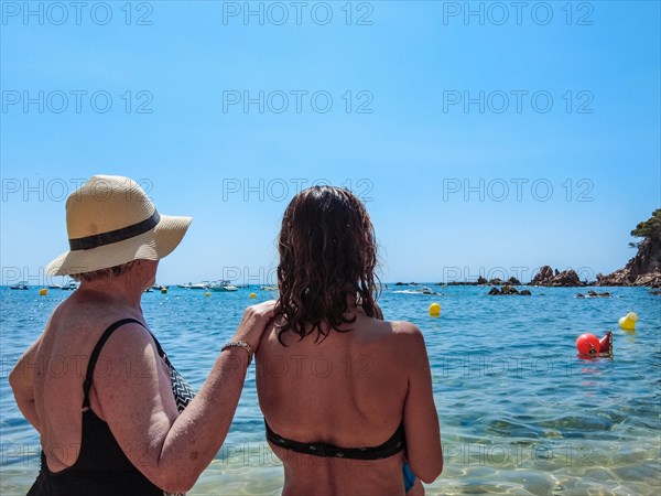 A family with their baby enjoying the summer in Cala Canyet next to the town of Tossa de Mar. Girona