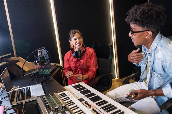 Caucasian woman and african man musician in studio recording a new album