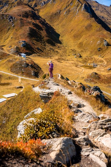 Wanders' woman on the way to the summit cross in rocky mountain landscape in autumn