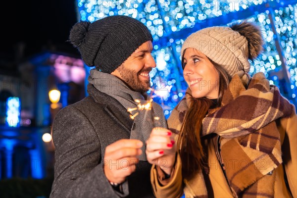 Winter portrait of a Caucasian couple enjoying the Christmas lights with torches in hand