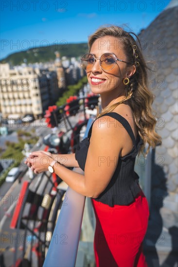 Blonde woman spending her holidays in a luxury hotel on a terrace looking at the city