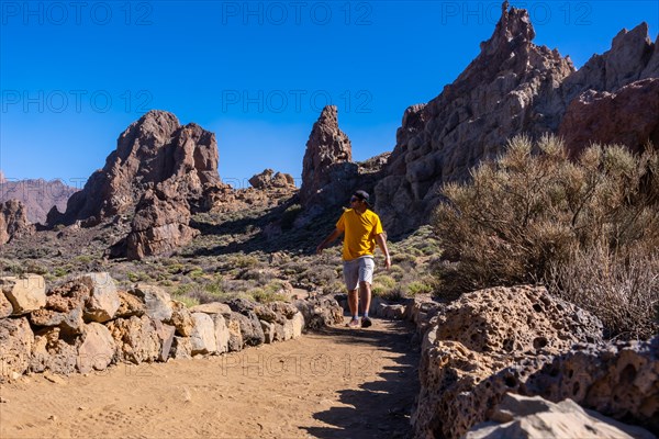 A tourist walking next to the Roques de Gracia and the Roque Cinchado in the natural area of Teide in Tenerife