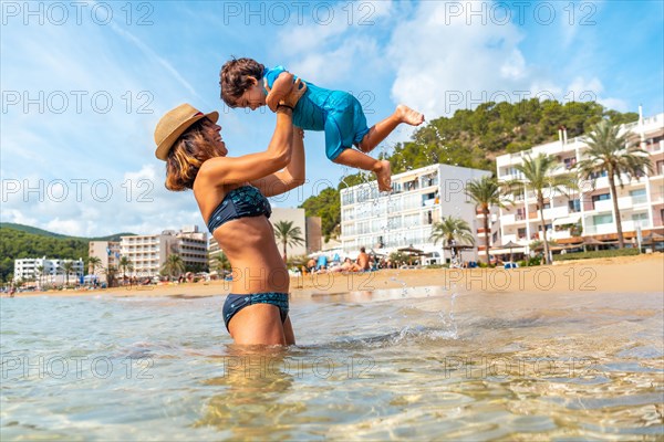 Mother lifting and playing with her son in the sea