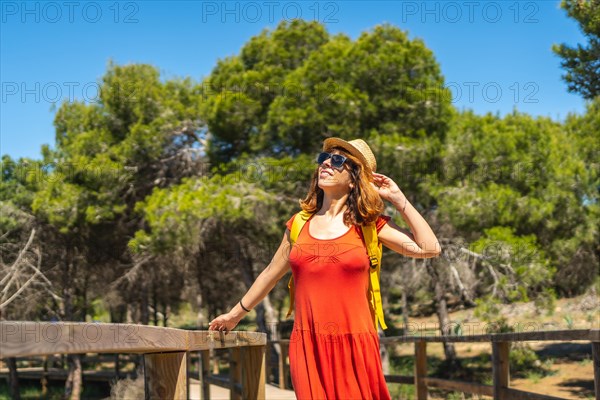 A young woman in a red dress on the path to the Moncayo Beach of the Mediterranean Sea in Guardamar del Segura