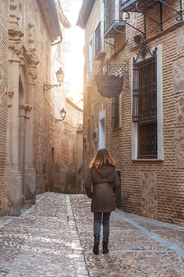 A tourist walking at sunset in the medieval city of Toledo in Castilla La Mancha