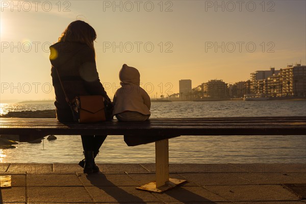 A young mother with her baby enjoying the sunset at Playa del Cura in the coastal town of Torrevieja