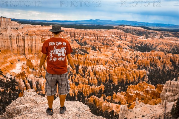 A young man with a red shirt looking at the national park from Bryce Point