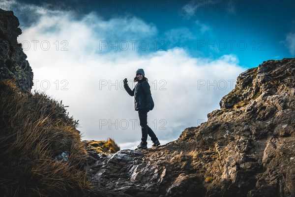 A young woman with winter hat waving on top of the mountain of Aiako Harriak