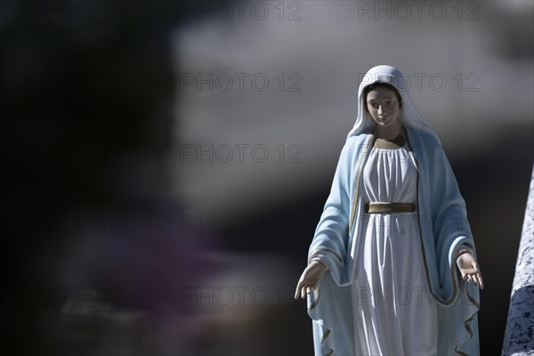 Kitschy figure of the Virgin Mary on a grave in a cemetery