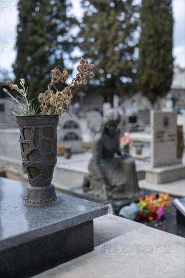 Vase with withered flowers on a grave in a cemetery