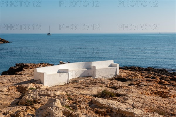 A white seat by the sea in the coastal town of Torrevieja next to Playa del Cura