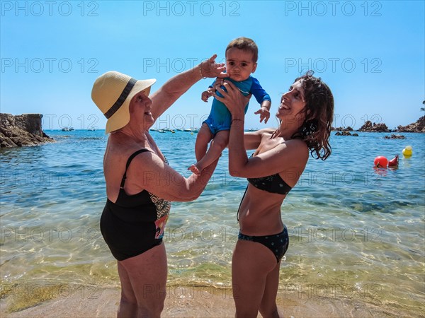 A family having fun in the summer in Cala Canyet next to the town of Tossa de Mar. Girona