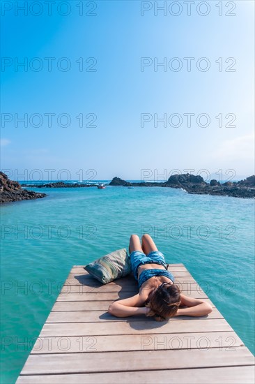 A young woman lying on the wooden walkway on Isla de Lobos