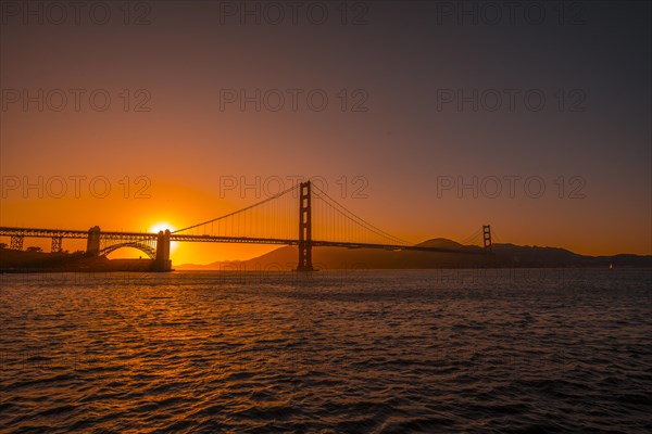 Red sunset at the Golden Gate of San Francisco with the sun hiding on the bridge. United States