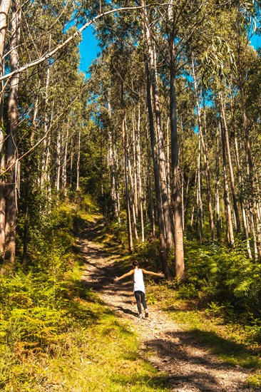 A young woman in a white T-shirt happily strolling in the Listorreta Natural Park in the town of Errenteria in the Penas de Aya or Aiako Harria Park. Gipuzkoa