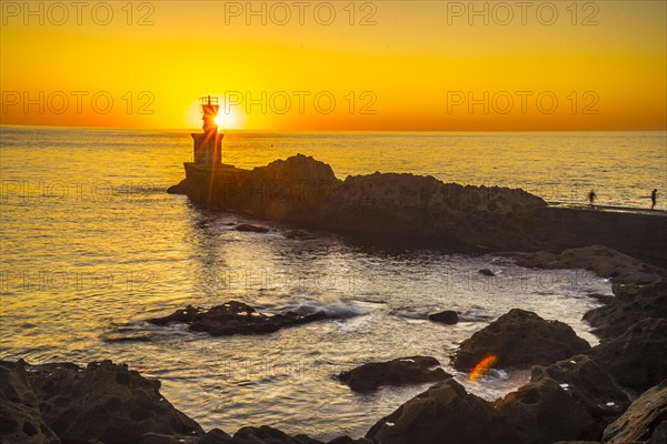 Detail of the sun behind the lighthouse in the orange sunset of the town of Pasajes San Juan. Gipuzkoa
