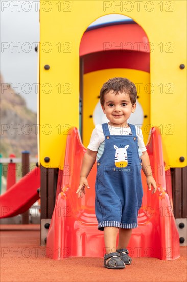 Baby playing in a playground having fun in summer