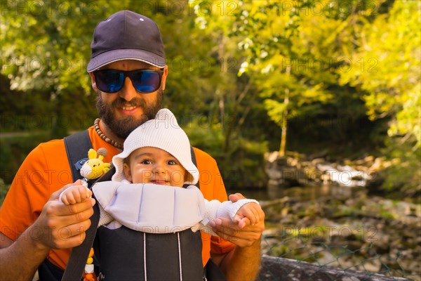 A father with the baby in a backpack heading to Passerelle de Holzarte in the forest or jungle of Irati