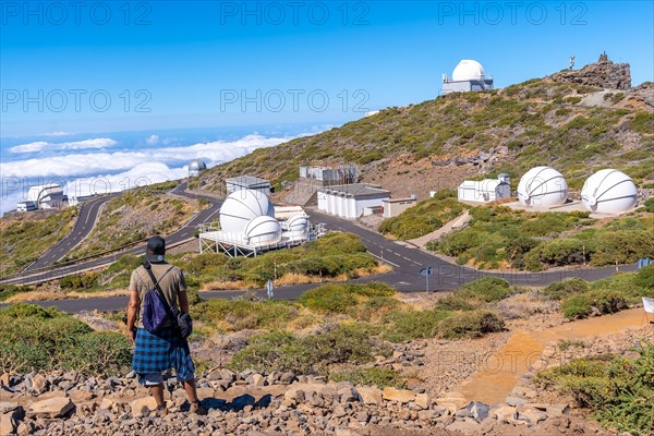 A young man on the trail looking at the telescopes of the Roque de los Muchachos national park on top of the Caldera de Taburiente