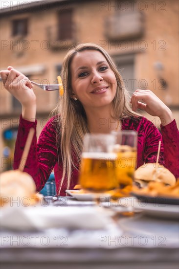 Blonde woman eating lunch in a red dress next to a medieval castle