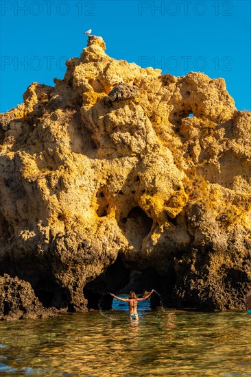 A woman in the water next to the rocks at Praia dos Arrifes