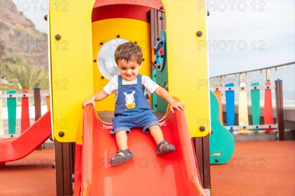 Boy playing in a playground having fun in summer and getting off the squeaker