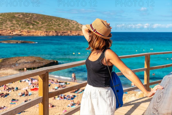 A tourist with a hat in spring at Cala Comte beach on the island of Ibiza. Sunset. Balearic