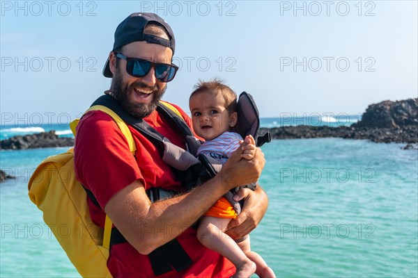 A young father with his son on vacation on the wooden walkway by the sea on Isla de Lobos