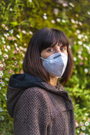 A young woman with a mask on her first walks in mistrust. First walks of the uncontrolled Covid-19 pandemic